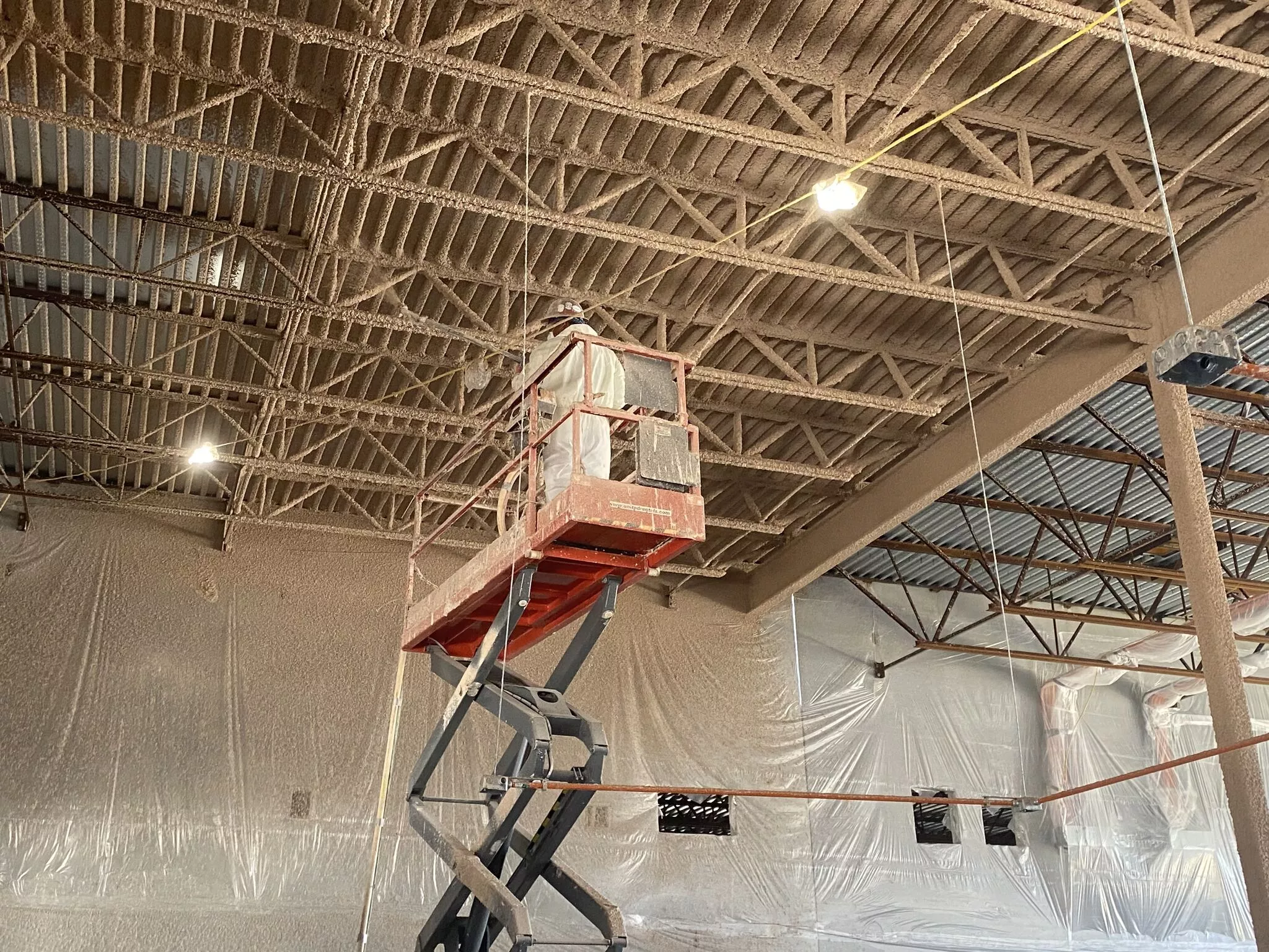 Spray fireproofing being applied to a ceiling in a large commercial building